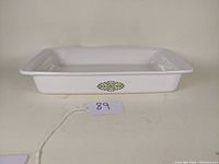 Full view of the rectangular white ceramic casserole dish with green pattern on side.