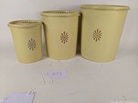 Front view of 3 vintage Tupperware Harvest Gold canisters arranged by size, showing lids and floral design.