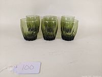 Front view showing six green glass tumblers with ivy texture and rounded base.