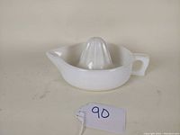 Side angle showing the white depression glass citrus juice reamer with square handle and pouring spout.