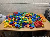 Large assortment of loose Mega Bloks scattered on a table, showing variety of colors and some specialized pieces.