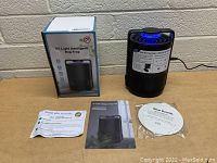 UV Light Intelligent Bug Trap device, box, manuals, thank you card and glue boards on wooden table.