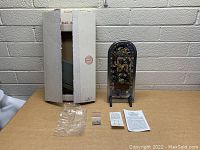 Photo shows the boxed stained glass collectible with easel stand, mounting hardware, and instructions arranged beside the box.