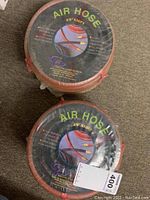 Two coiled and packaged air hoses stacked on top of each other showing the label and brand.