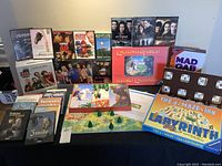 Lot includes four board games and multiple DVDs displayed on a black cloth.