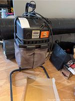 Premier Mega Catch MCP800 mosquito trap with collection bag and electrical cord draped over top, on a metal stand on hardwood floor.