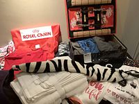 Photo showing assortment of shirts, scrubs, white towels, zebra print neck bean bag, and sushi set box