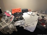Photo showing four clutch purses and two handbags with clothing items including grey blazer, white jacket, and sweaters.