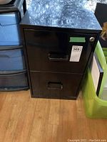 Front view of a black two-drawer metal filing cabinet with lock on top drawer and handle on each drawer.
