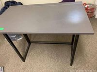 Grey folding table/desk shown from a top-down view highlighting the flat grey surface and black metal legs.