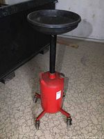 Front side view of the red portable oil drain with large black funnel and extendable neck on caster wheels.