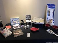 Full view of pet collection items including books, bowls, litter scoop, creamers, basket, adhesive roller, and stuffed toy.