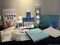 Photo showing entire lot including porcelain figurines boxes, cat window seat, scrapbooking supplies on table, ceramic platter, peacock wall art, Bombay picture frame, and metal cat signs on wall and table.