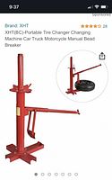 Online product image showing assembled red manual portable tire changer with bead breaker arm and base plate.