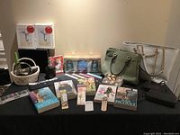 Image showing all lot items including purses, wristlets, skincare set, wall hooks, napkin rings, hair accessories, books, and nail files arranged on a table