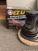 EZ Liner branded box showing product benefits and features, alongside an electric car waxing/polishing tool with a round buff pad and power cord.