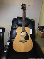 Full front view of the Yamaha F310 acoustic guitar showing the natural wood top, black pickguard, and six strings.