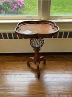 Full view of the wooden accent table showing scalloped top, wood base with metal spherical detail and three legs.
