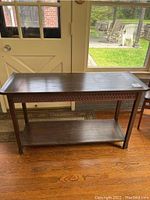 Full view of the dark wooden console table showing rectangular top, shelf, and legs.