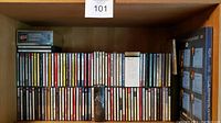 Full view of the CD collection in a wooden shelf showing multiple rows of classical and opera CDs in jewel cases, with a boxed set on the far right.