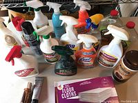 Photo showing various spray bottles and cleaning products including Rejuvenate Leather & Vinyl cleaner, Lysol Multi-Surface cleaner, Murphy Oil Soap, 409, and a pack of floor cloths.