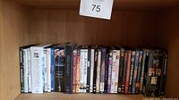 Photo capturing a variety of DVDs arranged side by side on a wooden shelf.
