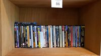 Shelf view showing a variety of DVD and Blu-ray cases arranged vertically on a wooden shelf.