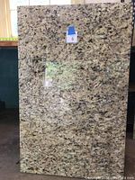 Full view of polished granite slab showing tan, brown, black, and cream speckled pattern