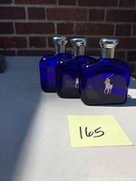 Three cobalt blue glass bottles of Ralph Lauren Polo Blue men's cologne with silver caps, arranged in a row with visible Polo player logo on front.