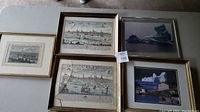 Overview of all framed prints and photos on surface, showing one print with broken glass.
