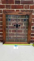 Front view of the stained glass window showing overall size and condition against a brick wall background.