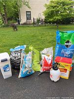 Full view of all items photographed on grass showing all bags and containers including the Miracle-Gro potting mix bag, sugar mulch, winter melt bag, yellow Preen container, and spray bottle.