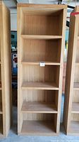 Front view of one wooden bookshelf showing five non-adjustable shelves with natural wood finish.