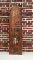 Front view of the antique wooden ironing board showing painted floral designs and inscription.