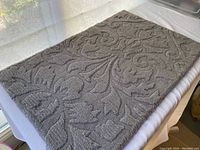 Full view of the rectangular gray hand-tufted rug showing overall design and shape on a white background near window light.