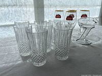 Wide shot showing all eight crystal glasses, four Stella Artois beer glasses, and wine aerator on a flat surface with light behind.