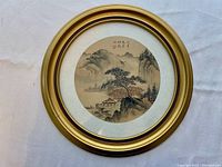 Front view of the framed round picture showing the detailed circular artwork of a landscape with Asian calligraphy and gold frame.