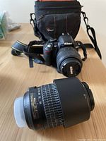 Nikon D3100 with attached 18-55 mm lens positioned in front of Lowepro camera bag; 55-200 mm lens in foreground