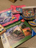 Overview of items showing Ravensburger puzzles, Perler beads, Zener Fable game, and pink carrying bag with unicorn designs