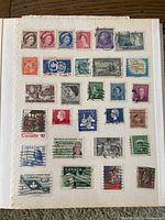 Photo of a stamp album page showing Canadian stamps featuring historic figures, monarchs, and landmarks with some postmarks.