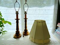 Pair of wooden table lamps with beige fabric shades placed beside them on a table against a window showing overall condition and scale.