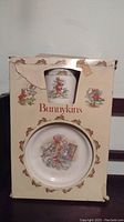 Front view of box containing Bunnykins children's bowl and cup, showing vintage Bunnykins design on cardboard box with wear and tear.
