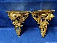 Front view of the pair of antique Italian wood and gesso wall sconce shelves with gold gilt finish.