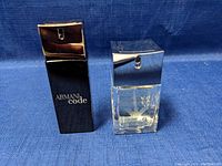 Two bottles of Armani Code perfume, one black and taller, the other clear and shorter, shown front view.