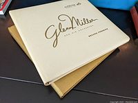 Photo of one album with a white cover labeled Glenn Miller and his Orchestra, Second Pressing by RCA Victor.