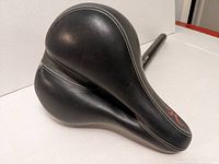 Front angled view of black Velo Via bike seat showing leather-like surface and white stitching.