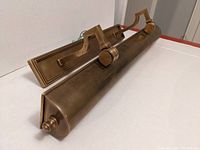 Side angle view of the brass picture light showing its substantial construction and adjustable mounting bracket.