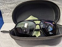 Front view of black aviator sunglasses inside a hard zippered case with cleaning cloth