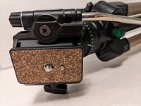 Close-up of the tripod quick-release mounting plate with cork surface and mounting screw.