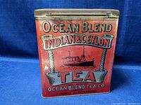 Front view of the vintage tea metal cannister showing the Ocean Blend Indian & Ceylon Tea branding, ship illustration, and red color.